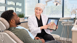 Dentist explains a root canal tooth illustration with a crown to a patient at All Smiles Dentistry in Allen, Texas.